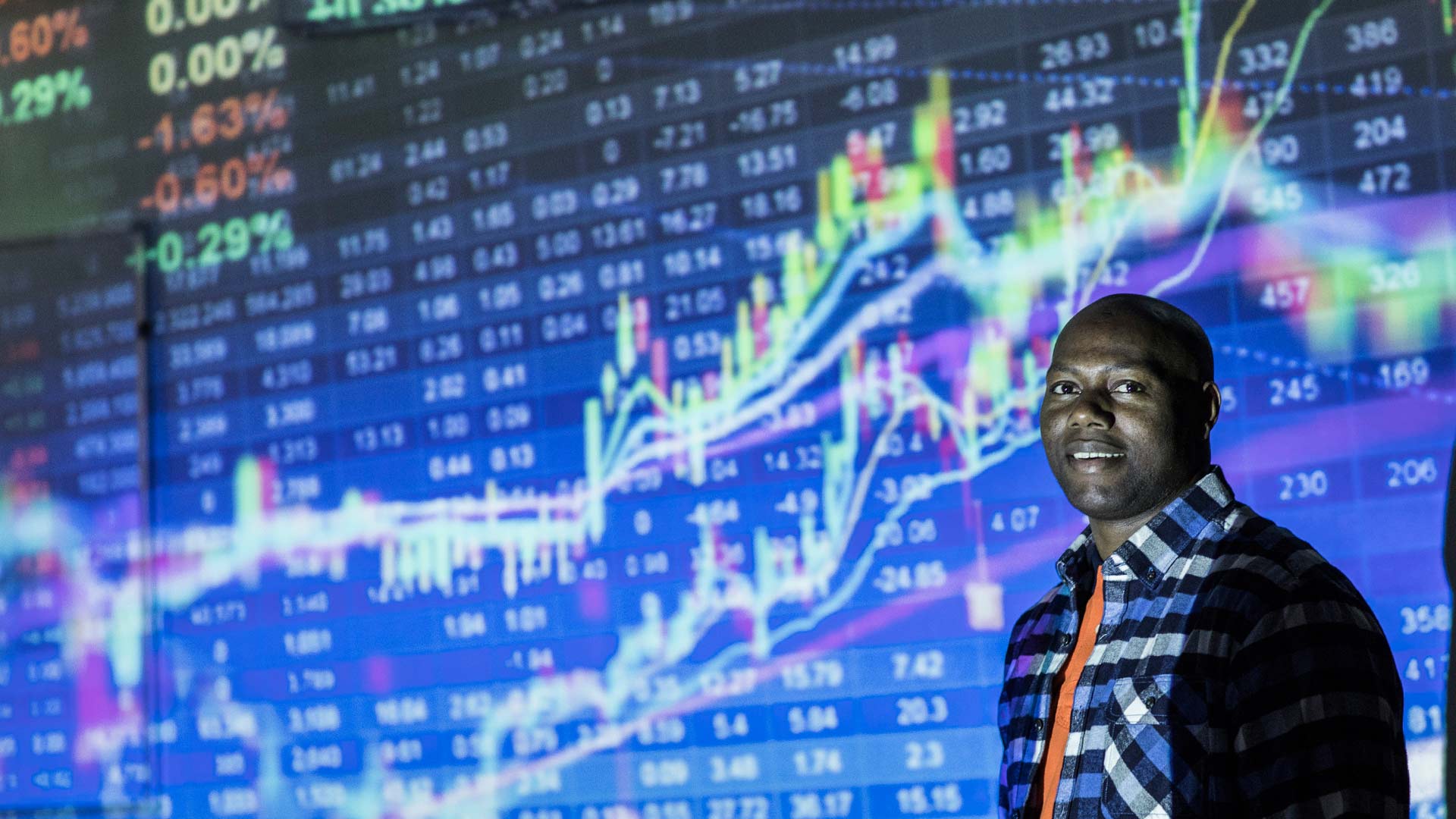 Student stood in front of stock market figures