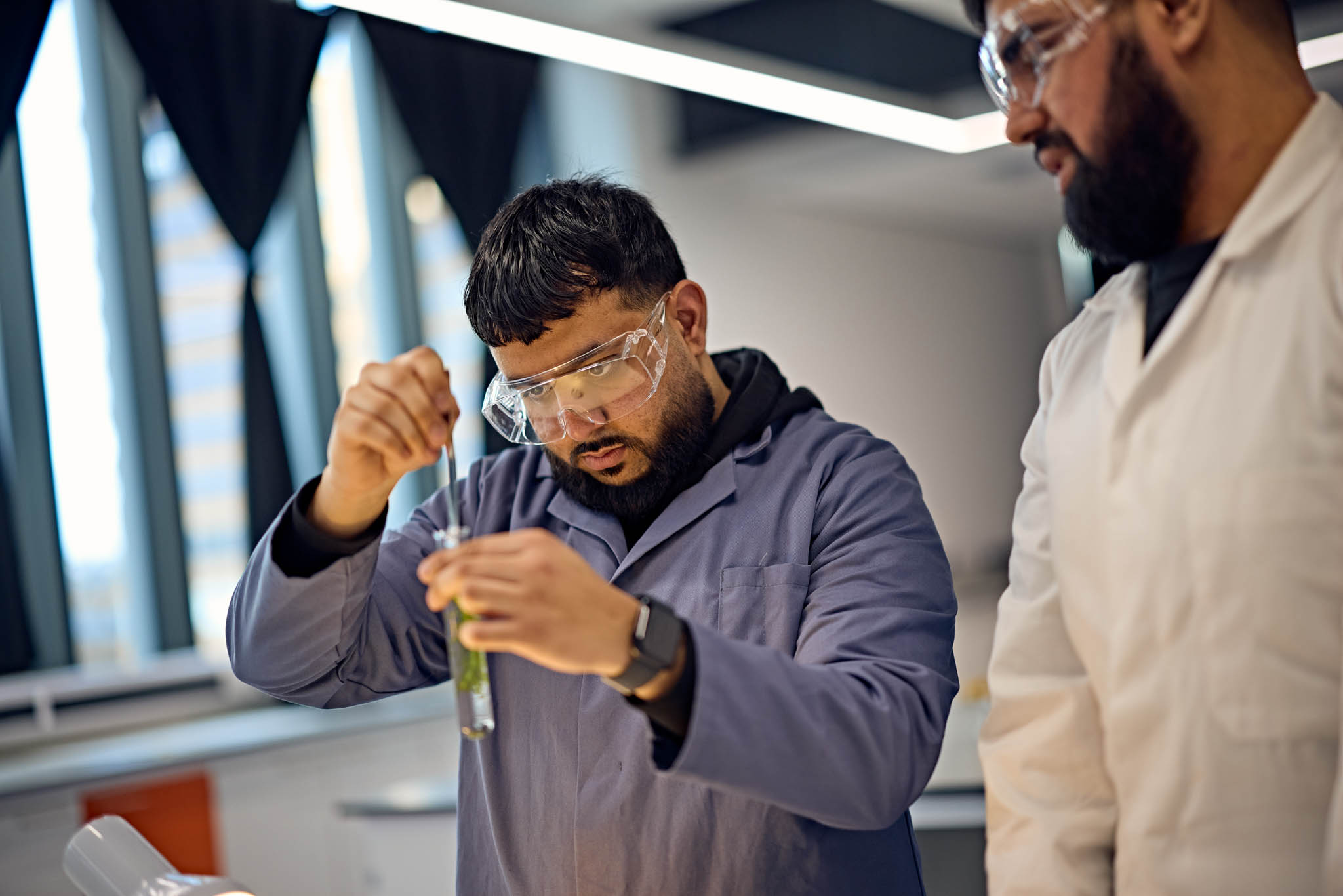 Student undertaking a science experiment under the supervision of a teacher