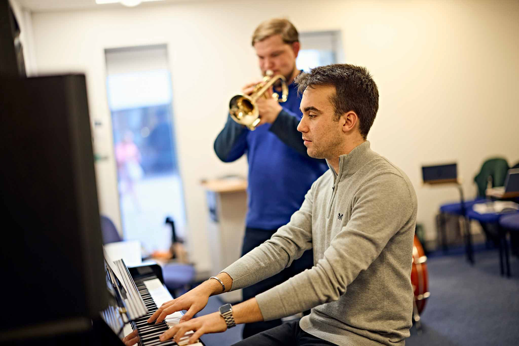 Music lesson with one student playing the piano and one playing the trumpet