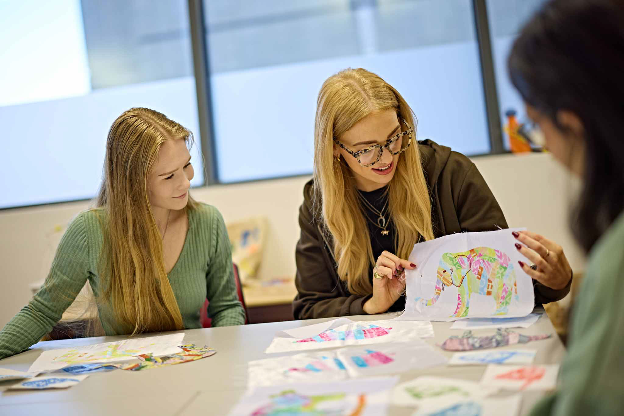 Students sat at a crafting table showing off their designs