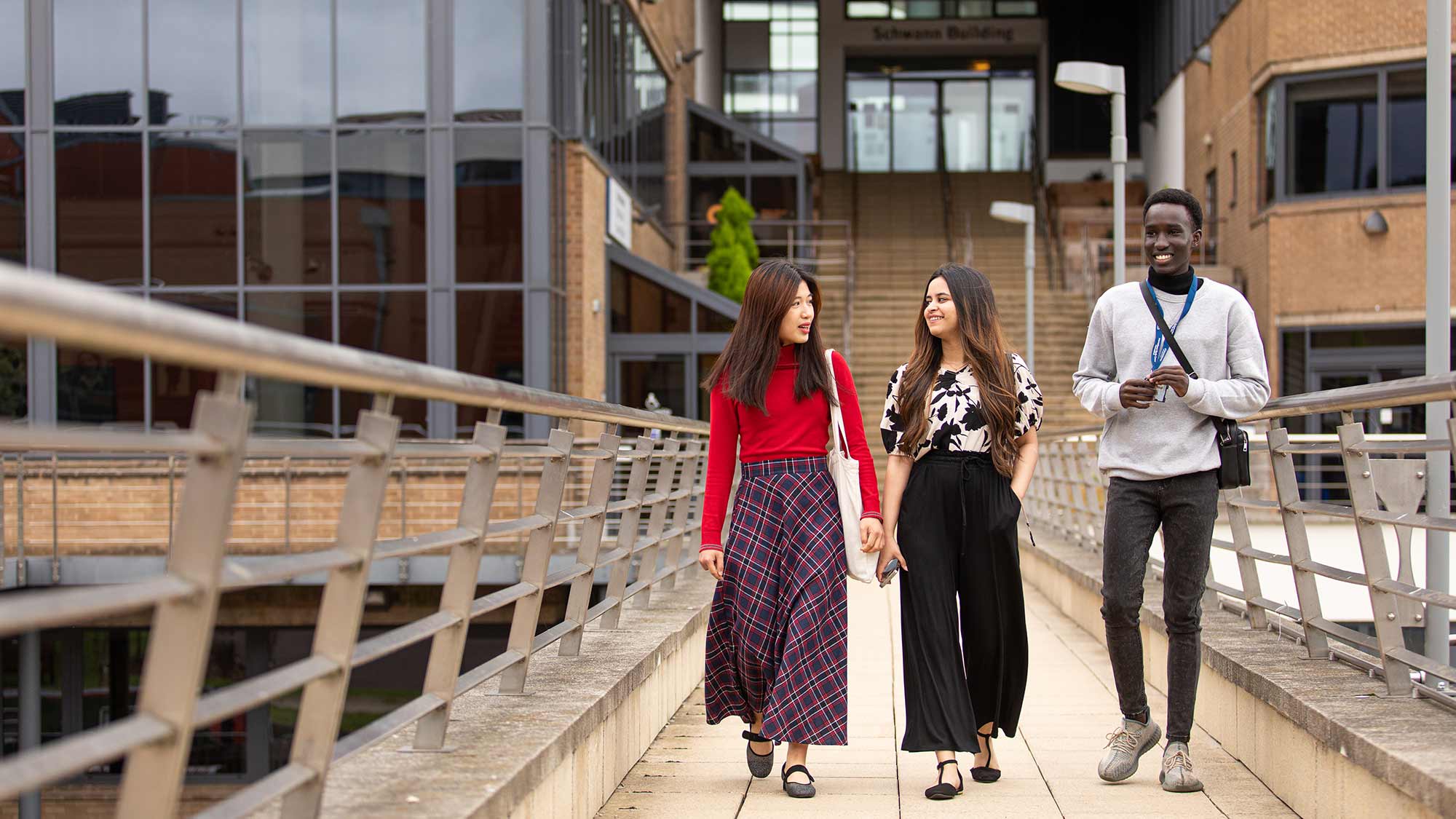 Students walk together along the bridge over the canal at the University of Huddersfield campus