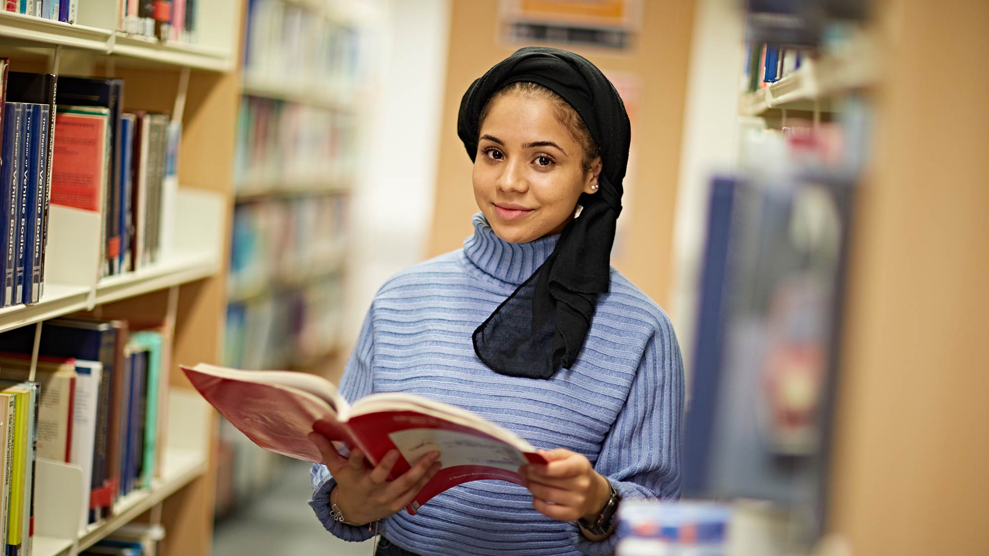 A student reading a book in the University library