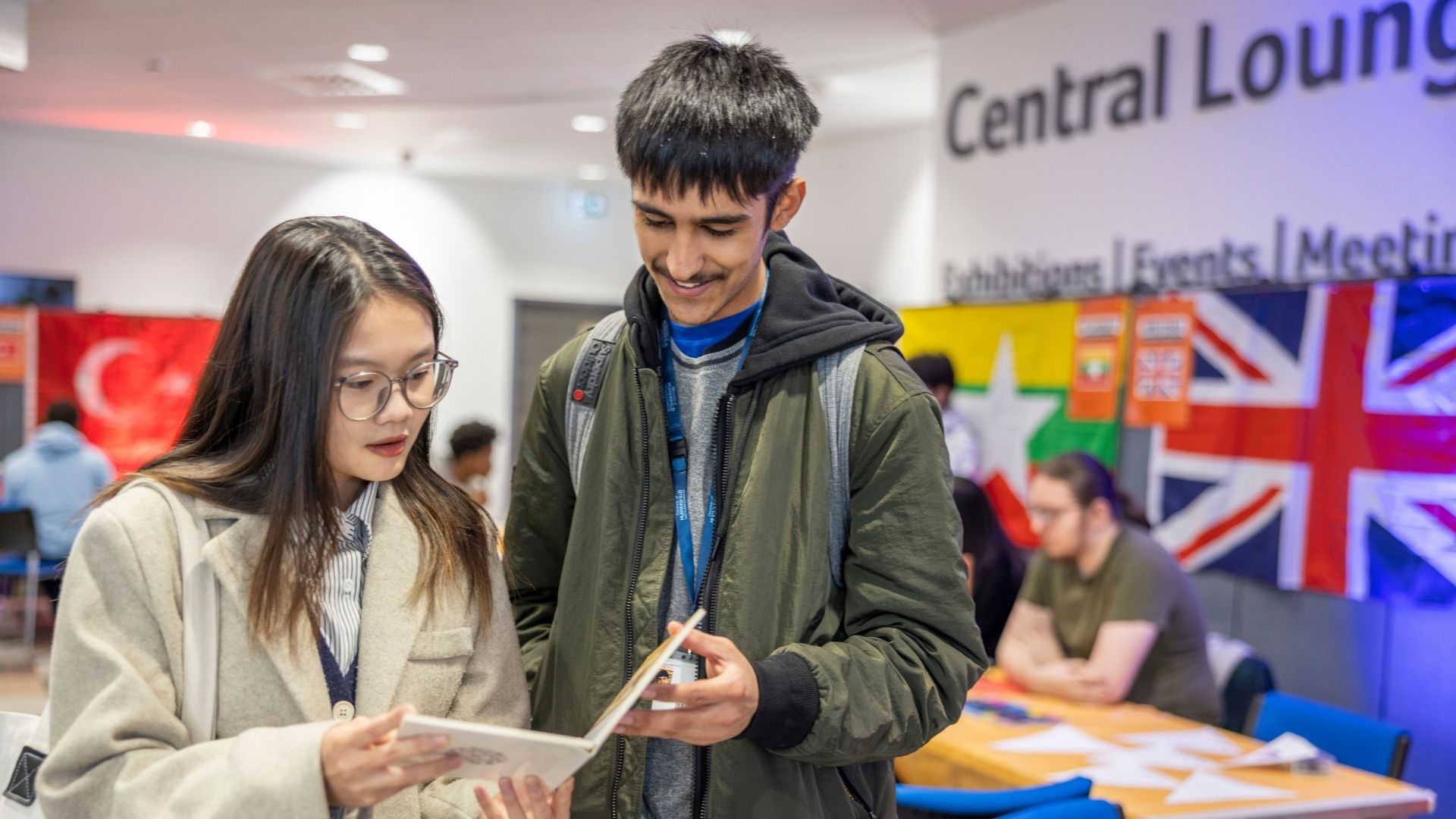 Students reading brochure at international fair on campus
