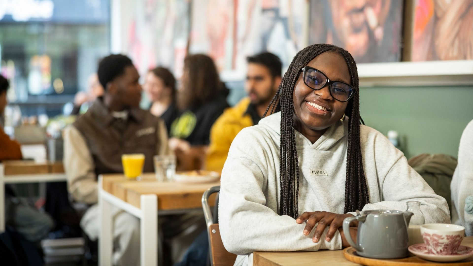 Student smiling at camera sitting at table at cafe in Huddersfield town centre