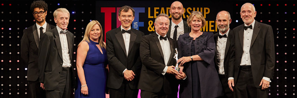 University of Huddersfield's Vice-Chancellor, Professor Bob Cryan (centre) receives the award from Alison Johns, CEO of AdvanceHE. Also pictured (l-r) are Richard Ayoade, Colin Blair, Siobhan Campbell, Professor Tim Thornton, Danny Benton, Matt Mills and Andrew McConnell