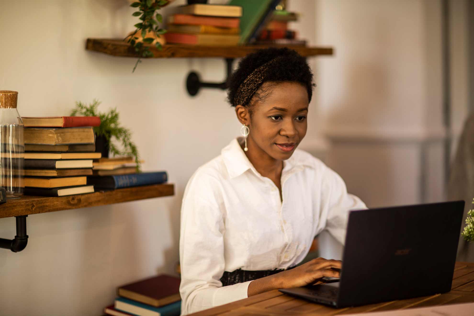 student on laptop with books behind