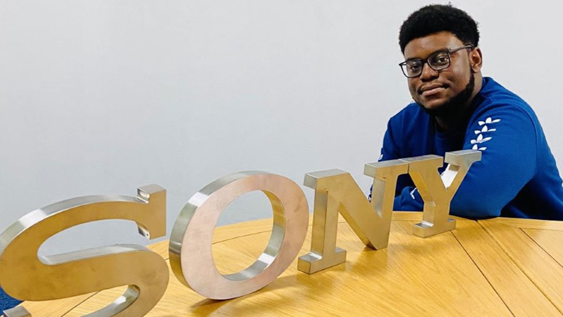 A profile photo of John Calvin posing next to the Sony logo